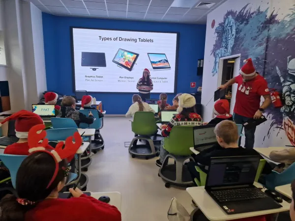 Dzieci w czapkach Mikołaja siedzą w Pracowni przy komputerach – 