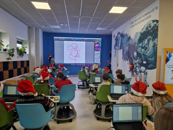 Dzieci w czapkach Mikołaja siedzą w Pracowni przy komputerach – 