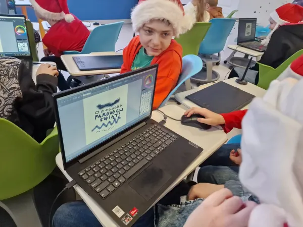 Dzieci w czapkach Mikołaja projektują bombki na laptopach przy pomocy tabletów piórkowych – 