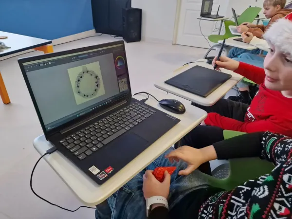 Dzieci w czapkach Mikołaja projektują bombki na laptopach przy pomocy tabletów piórkowych – 