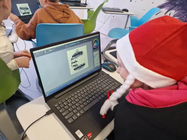Dzieci w czapkach Mikołaja projektują bombki na laptopach przy pomocy tabletów piórkowych – 